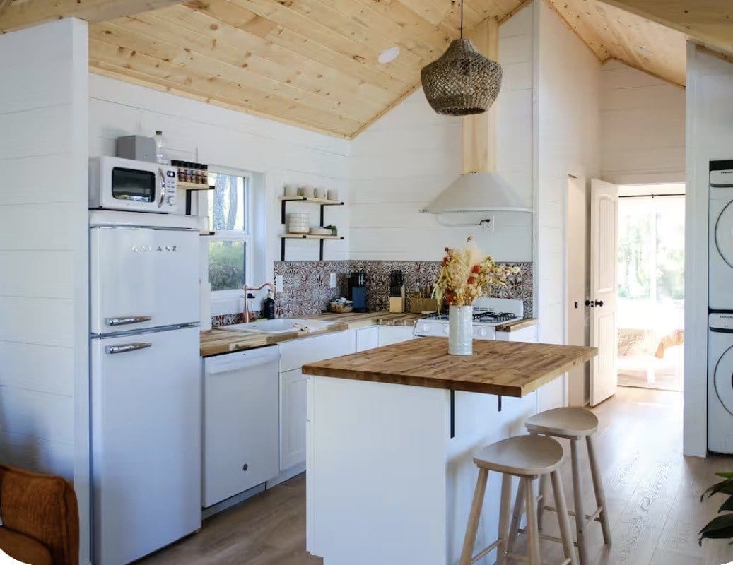 Finished interior with a vaulted pine ceiling, white shiplap walls, a retro fridge and a butcher-block kitchen island